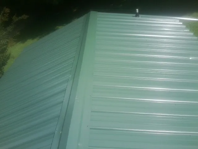 New green metal panels meeting at the ridge of a roof — Flat Roof Repair work by our crew in Nevada