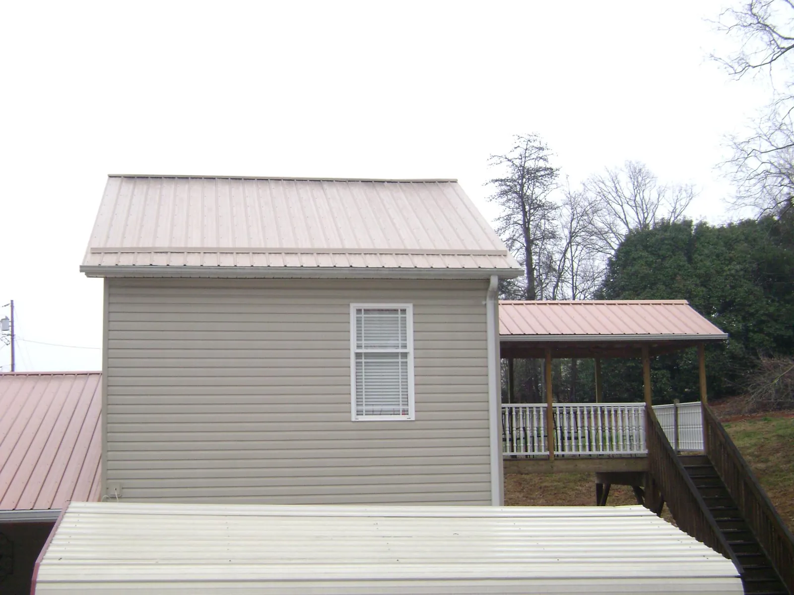 Tan metal roofs on a two story addition and attached porch, from a Roof Replacement job in Nevada